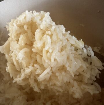 cooked white rice on a wooden spoon.